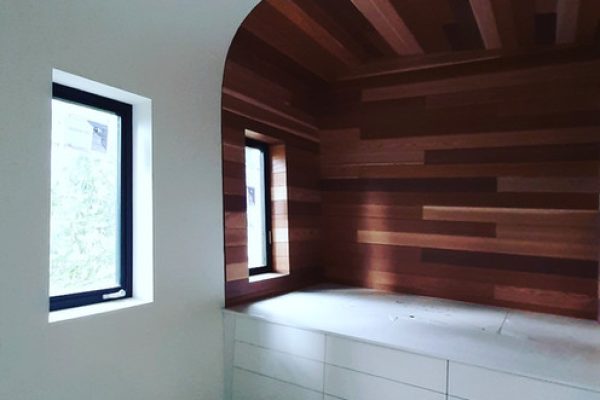 Interior of a room with a wooden wall and a window, allowing natural light to illuminate the space.